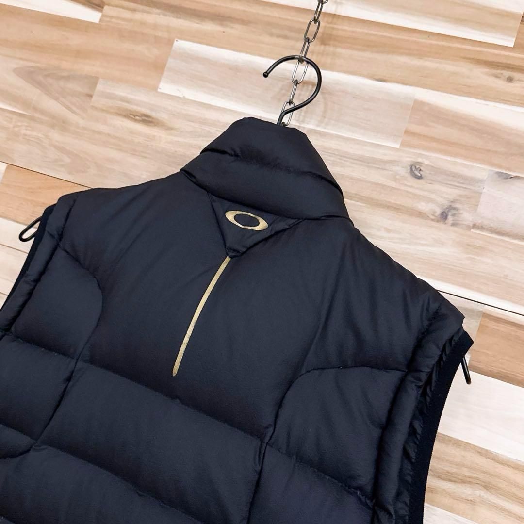 【オークリー】フェザー ブレンド スカル ロゴ ダウンベスト ゴルフ M 黒×金 オークリー】フェザー ブレンド スカル ロゴ ダウンベスト ゴルフ M 黒