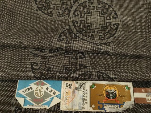 平和屋着物 本場大島紬 純泥染 手織り 一元7マルキ 唐草丸文 たかし紬謹製 証紙付き 正絹 ck