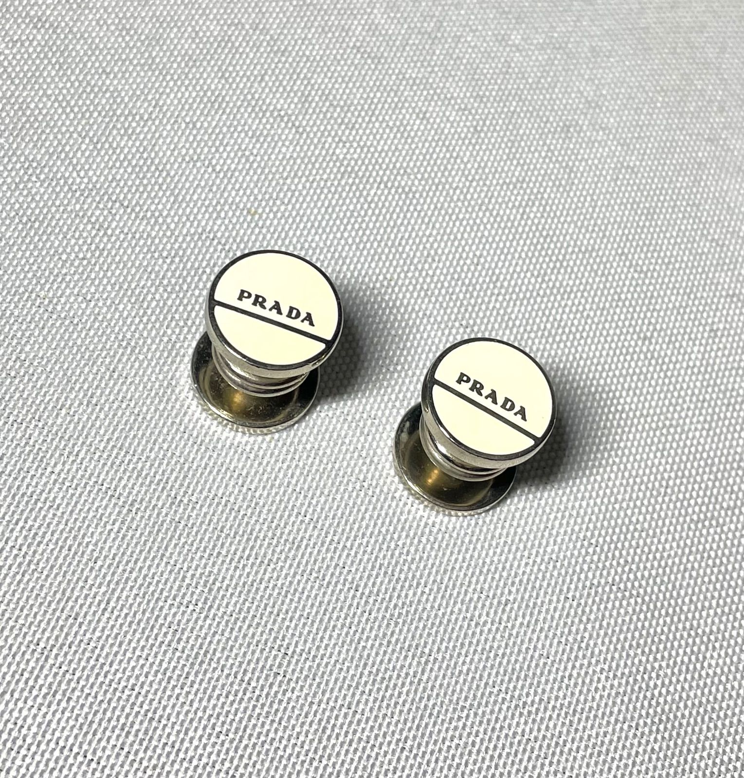 PRADA プラダ ブランドロゴ文字 ホワイト&シルバー ボタン式オーバル