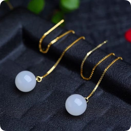 ゴールドのロングチェーンにホワイトジェイドのボールが揺れるエレガントなデザインのピアス