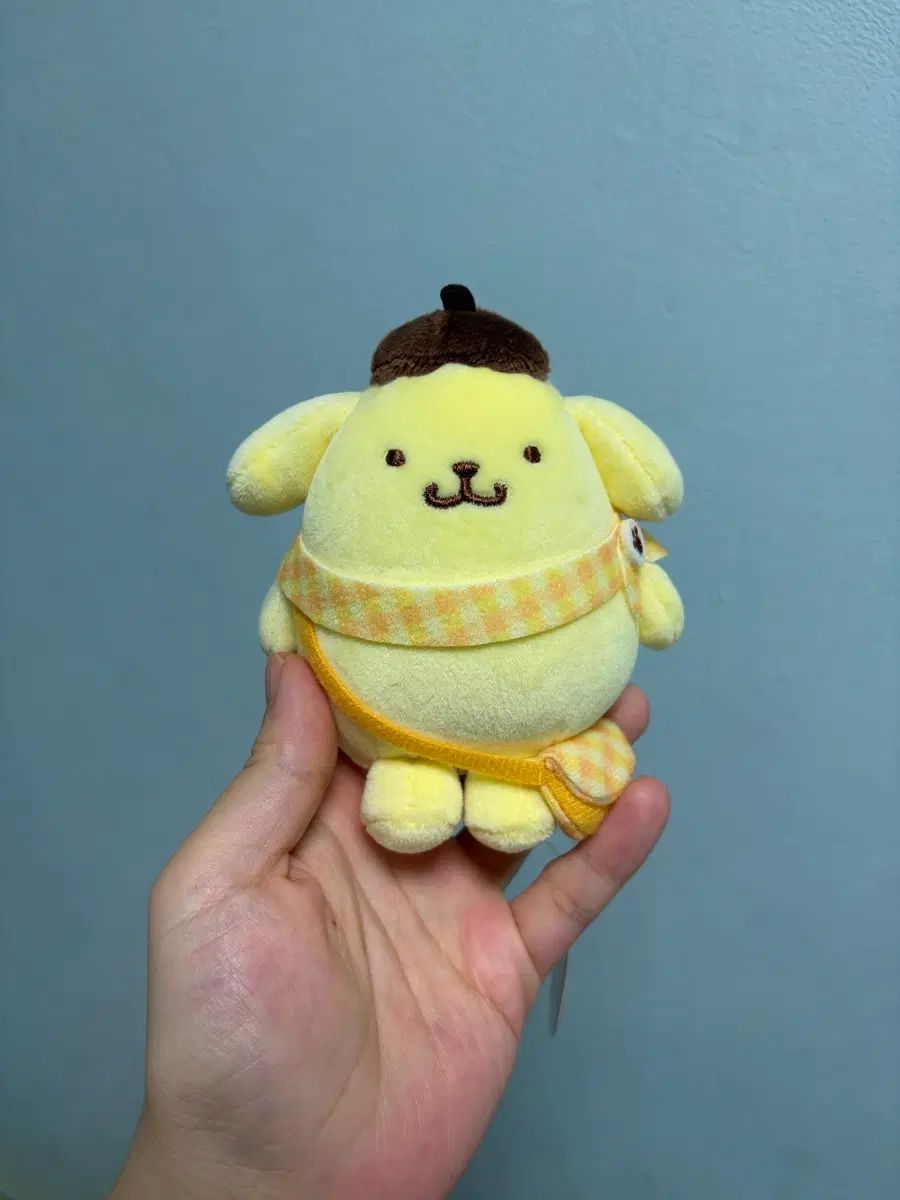 リュックサック旅行バッグを背負っているポムポムプリンのマスコットぬいぐるみ