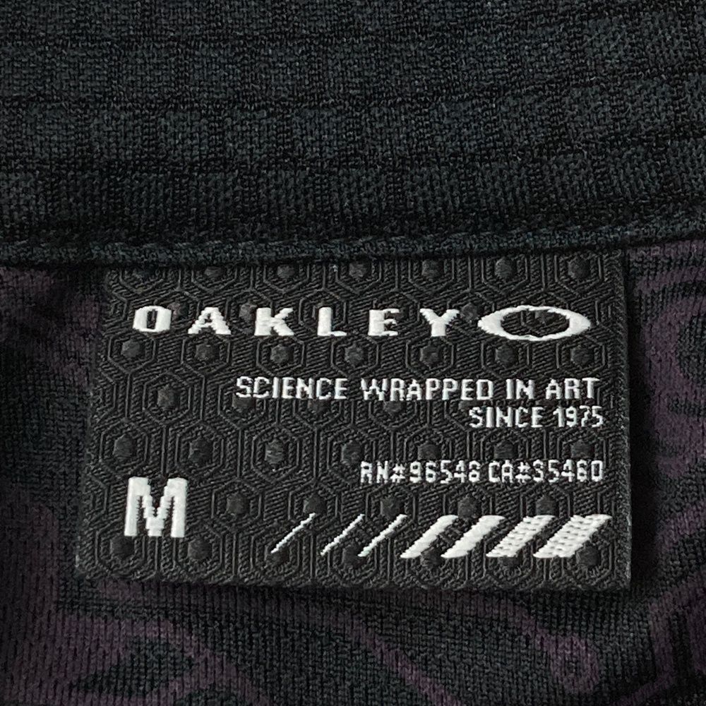 サイズ：M OAKLEY オークリー  モックネックブルゾン 総柄 パープル系 [240101478165] ゴルフウェア メンズ ストスト OAKLEY オークリー モックネックブルゾン 総柄 パープル系