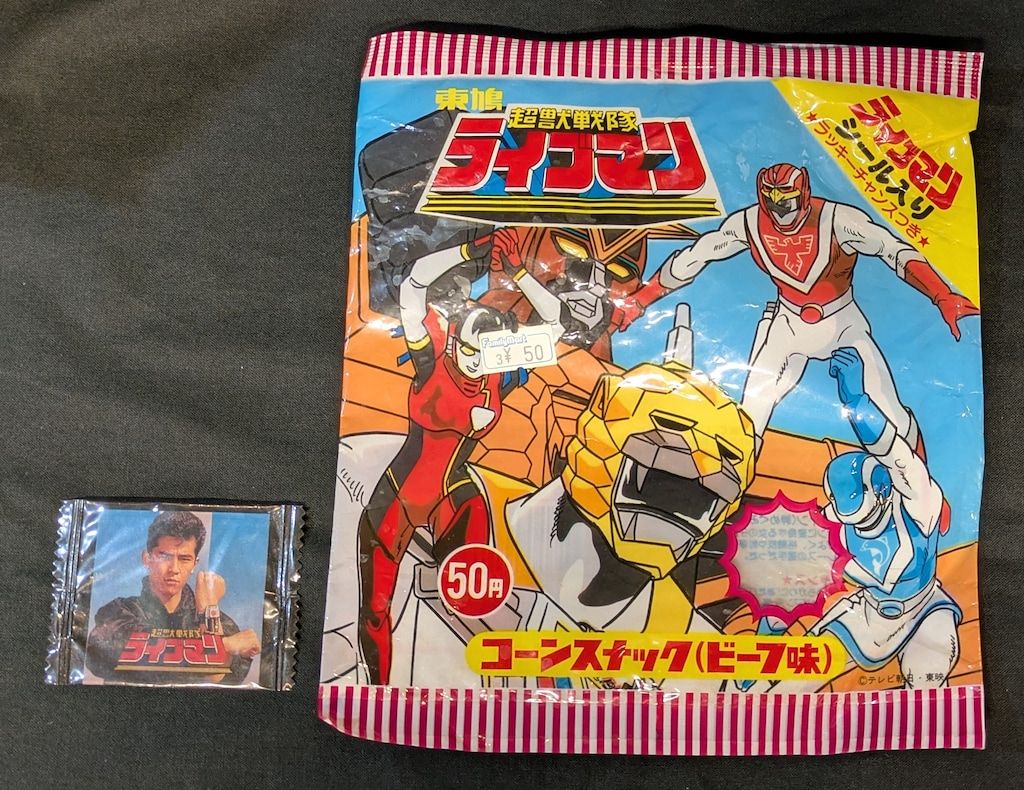東鳩 菓子パッケージ|ライブマンコーンスナック 中心にイエロー 右上にレッド 青背景 ビーフ味