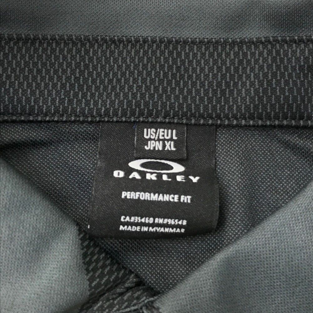 サイズ：XL OAKLEY オークリー FOA400844 半袖ポロシャツ ロゴプリント 総柄 ブラック系 [240101472864] ゴルフウェア メンズ ストスト サイズ：XL OAKLEY オークリー FOA400844 半袖ポロシャツ ロゴ