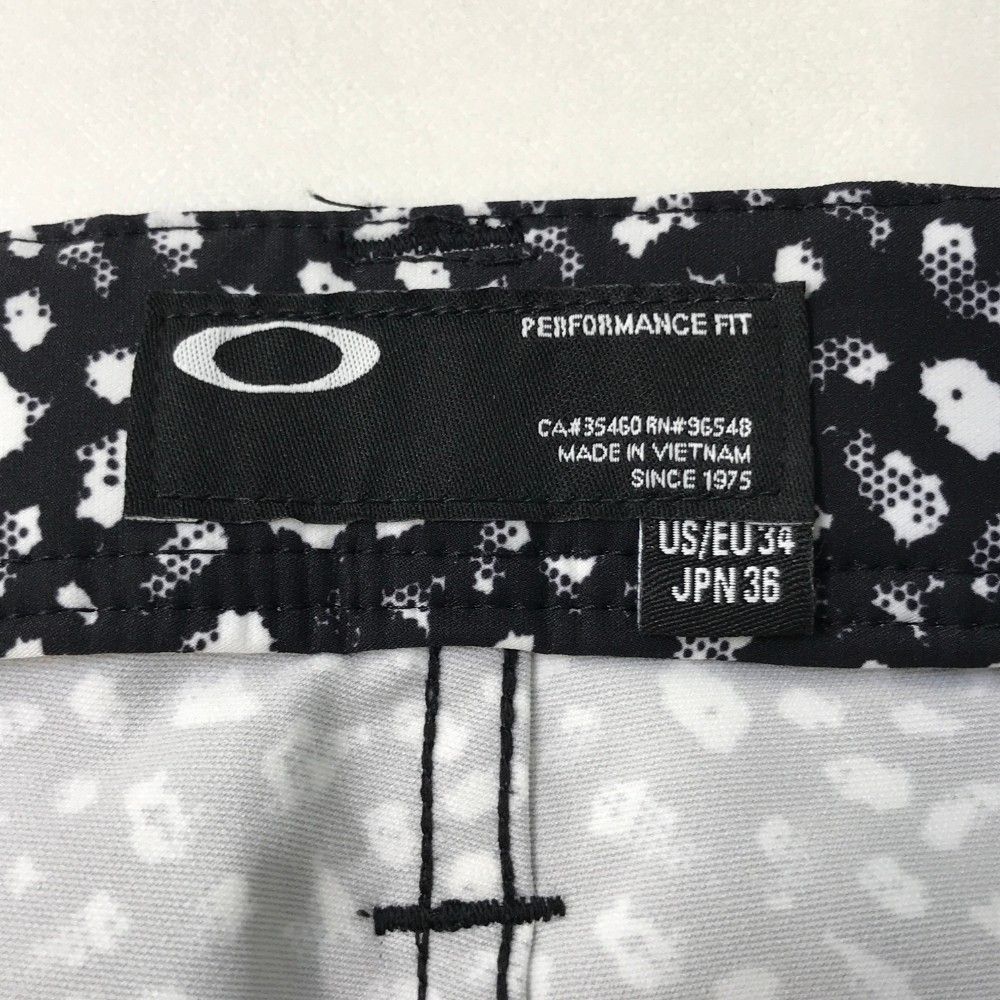 サイズ：36 OAKLEY オークリー 422645JP ロングパンツ スカル刺繍 総柄 ブラック系 [240101455306] ゴルフウェア メンズ ストスト サイズ：36 OAKLEY オークリー 422645JP ロングパンツ スカル