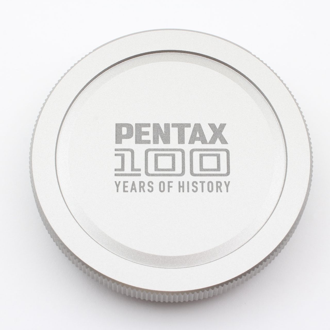 PENTAX 100周年記念ボディキャップになります。 ペンタックス100周年記念カメラボディキャップ - メルカリ