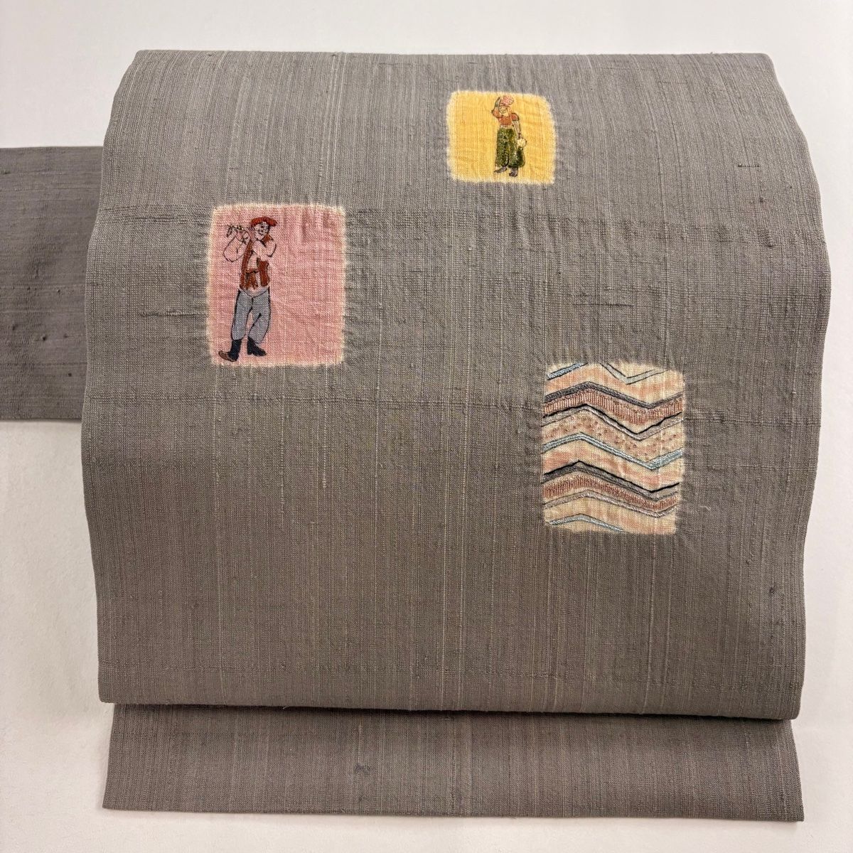 名古屋帯 秀品 紬地 人物 幾何学模様 刺繍 絞り 灰色 正絹