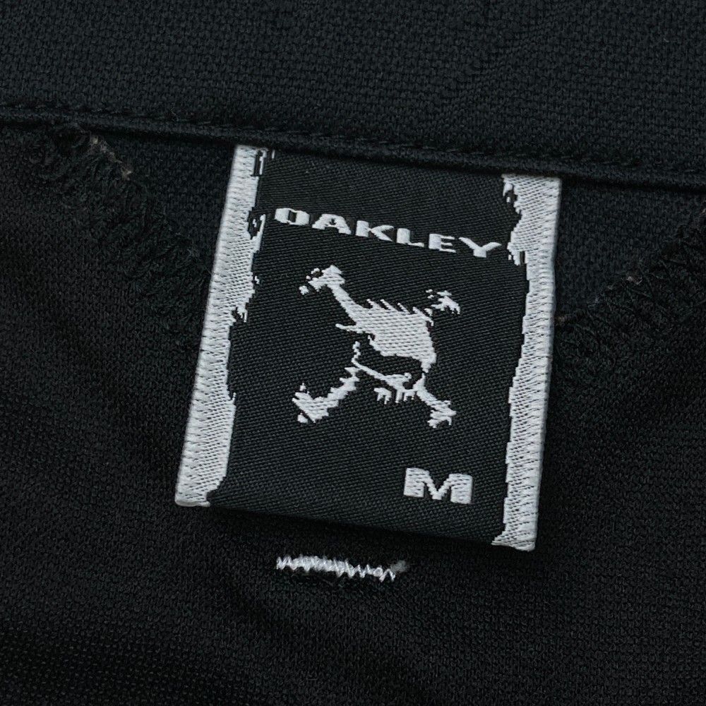 サイズ：XL OAKLEY オークリー  ハーフジップ半袖Tシャツ スカル刺繍 ネイビー系 [240101451951] ゴルフウェア メンズ ストスト サイズ：XL OAKLEY オークリー ハーフジップ半袖Tシャツ スカル