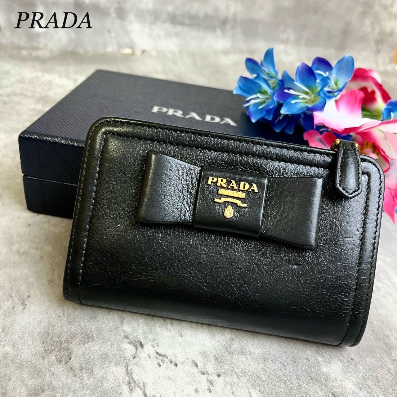 ✨良品✨ PRADA プラダ 二つ折り 財布 リボン ロゴ金具 ロゴ型押し ゴールド金具 ウォレット カードケース 定期入れ 小銭入れ レザー レディース  ブラック 黒色 - メルカリ