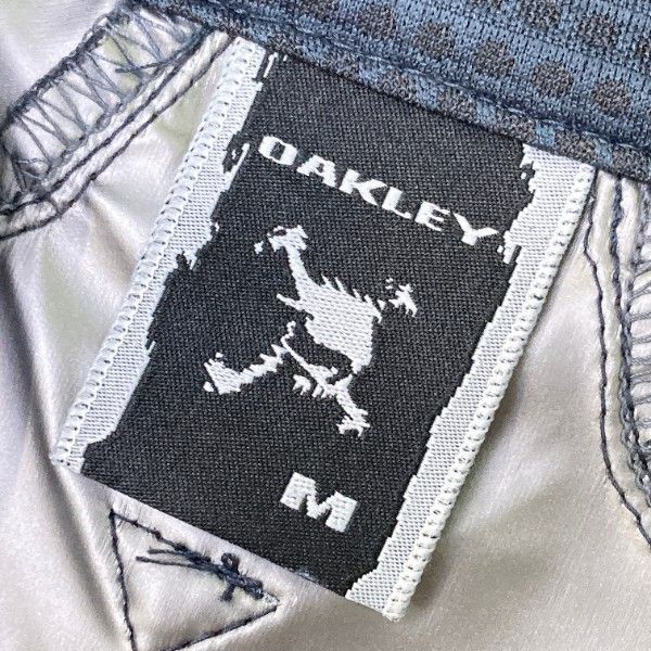 サイズ：M OAKLEY オークリー 411924JP 長袖ジャケット スカル刺繍 総柄 パープル系 [240101452318] ゴルフウェア メンズ ストスト OAKLEY オークリー 411924JP 長袖ジャケット スカル刺繍 総柄
