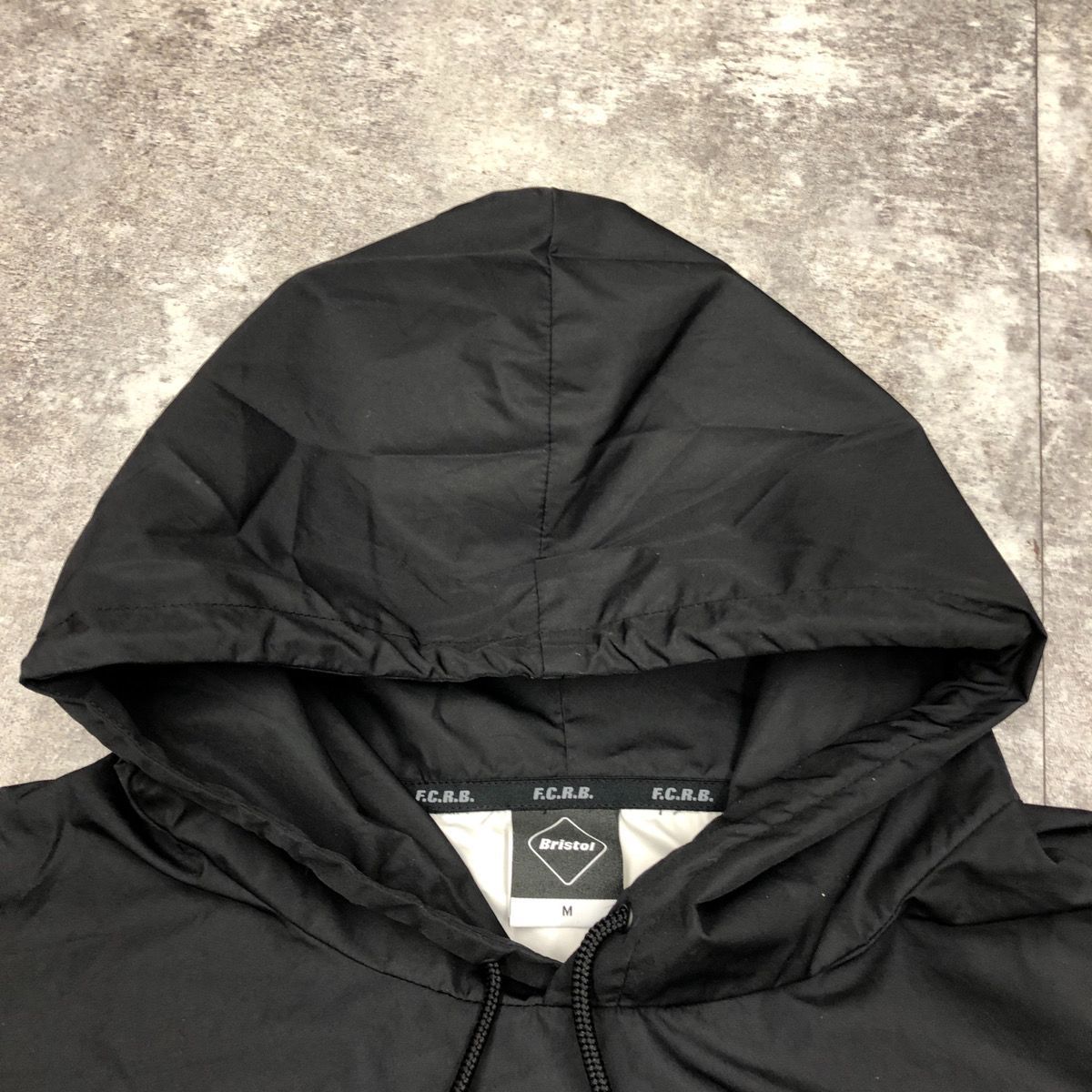 F.C.REAL BRISTOL エフシーレアルブリストル BACK STRIPE ANORAK ナイロンパーカー フーディー ライトジャケット  バックプリント ビックロゴ メンズ BLACK ブラック 黒 Mサイズ FCRB-178005 - メルカリ