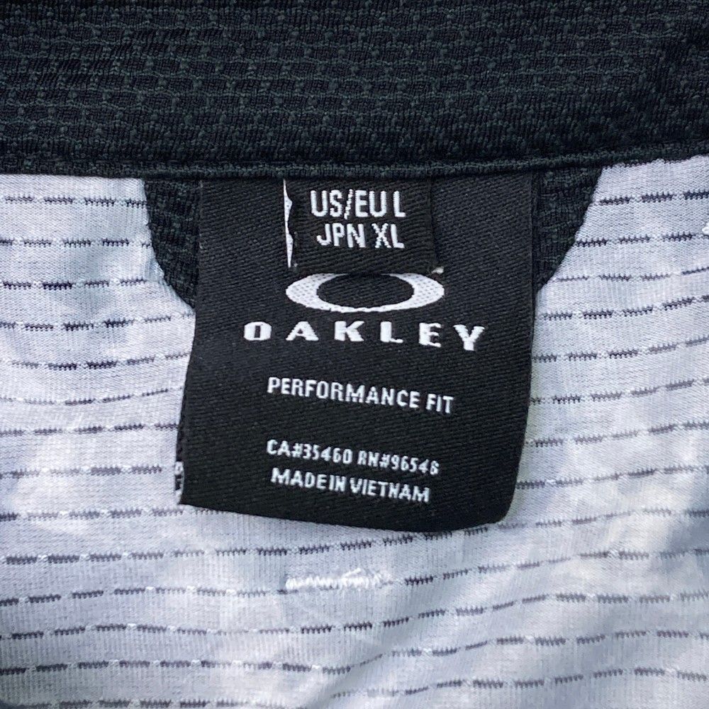 サイズ：XL OAKLEY オークリー  半袖ポロシャツ 総柄 ブラック系 [240101448099] ゴルフウェア メンズ ストスト サイズ：XL OAKLEY オークリー 半袖ポロシャツ 総柄 ブラック系