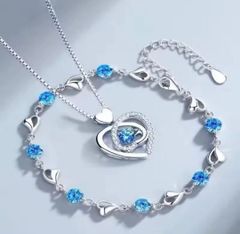 Silver heart necklace and bracelet set with blue stones. Elegant and cute accessories for women. Perfect as a gift for birthdays, anniversaries, or Christmas. Popular design. High-quality jewelry set.