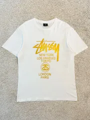 L まれ) STUSSY(ステューシー) STUSSY ワールドツアー 半袖 Tシャツ 白 ゴールド