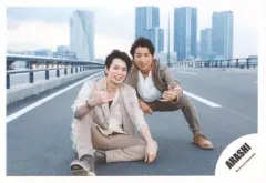 【中古】生写真(ジャニーズ) 嵐/松本潤・大野智/横型・全身・衣装ベージュ茶グレー白・松本座り・大野屈み・片手指2本立て・背景野外・道路・ビル/「Power of the Paradise」PV＆ジャケ写撮影/公式生写真