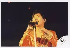 【中古】生写真(ジャニーズ) 嵐/二宮和也/ライブフォト・横型・バストアップ・衣装オレンジ・目線左・背景黒・右手マイク/公式生写真