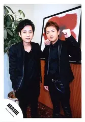 【中古】生写真(ジャニーズ) 嵐/二宮和也・大野智/膝上・衣装黒・二宮左手大野の肩・大野左手グー・背景赤白/「Sakura」PV＆ジャケ/公式生写真