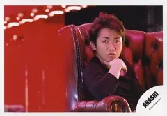 【中古】生写真(ジャニーズ) 嵐/大野智/上半身・衣装黒・ソファ座り・右手顎・背景赤・横型/公式生写真