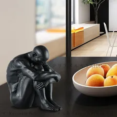 膝を抱えて座る人の置物